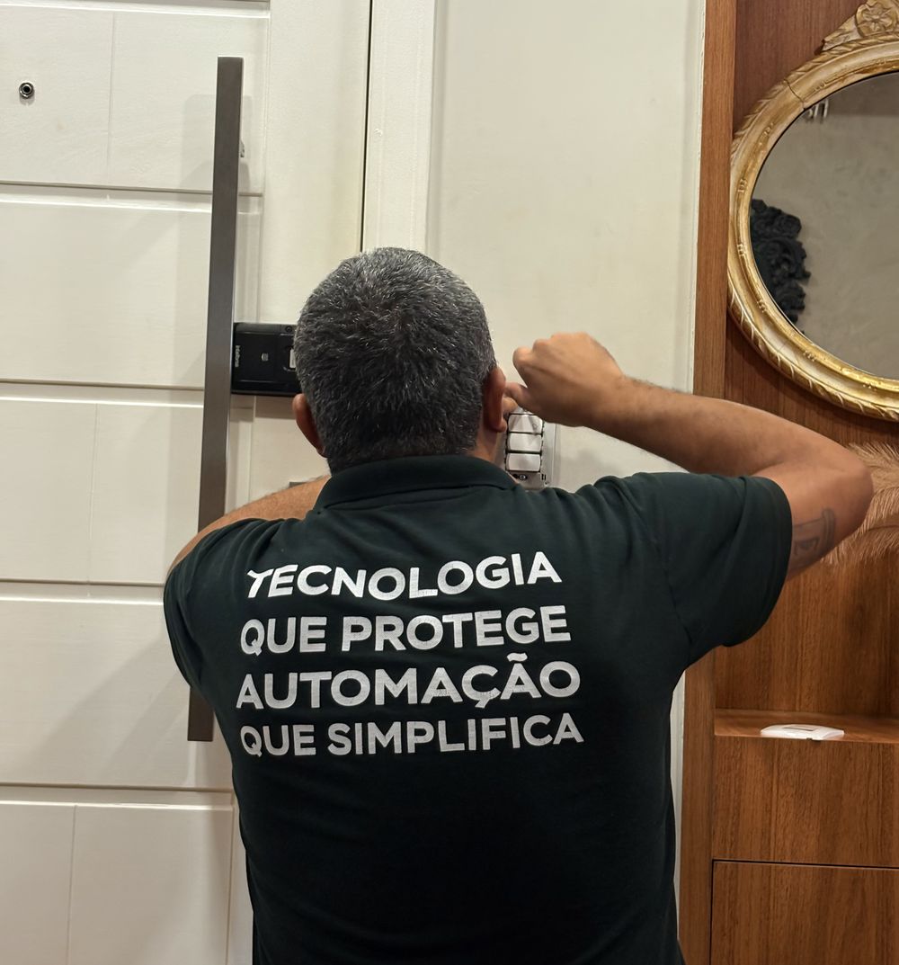 Técnico instalando a botoeira na parede, ao lado da porta de entrada de um apartamento no Rio
